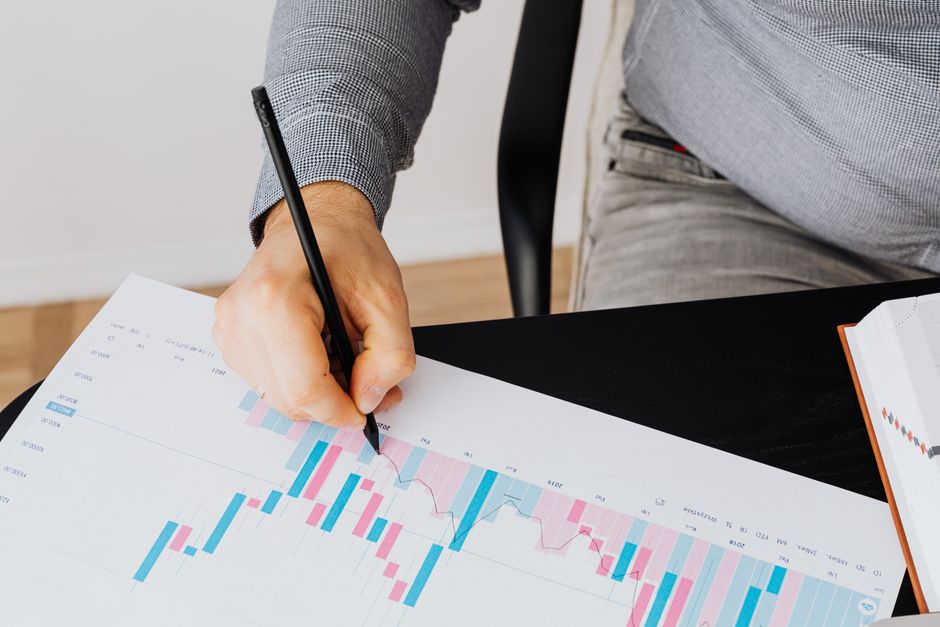 Detailed financial graph showing analysis by a person with a pen indoors.